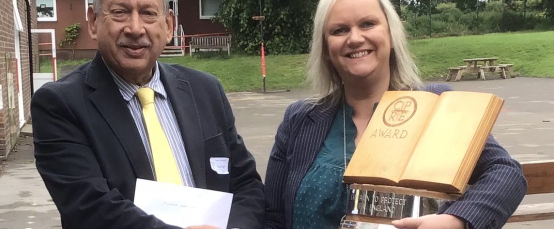 Two people at a school with the trophy