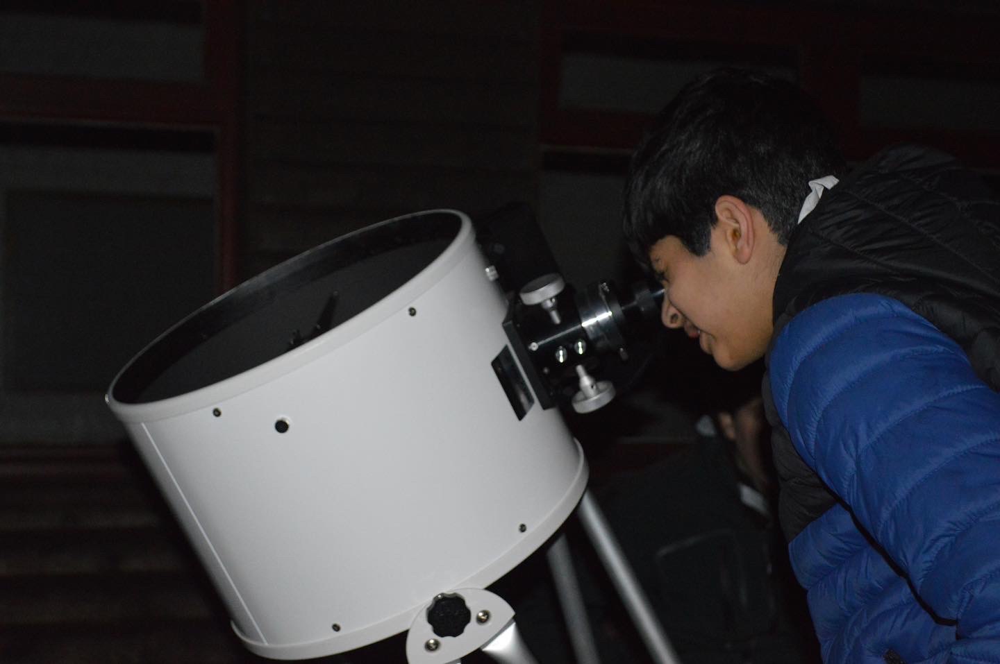A boy looks through a telescope