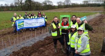 A group of people holding a banner and another group of people standing next to them in a field