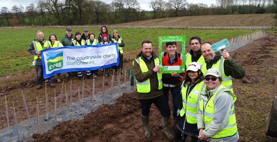 A group of people holding a banner and another group of people standing next to them in a field