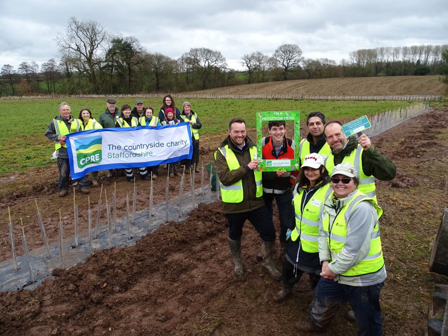 A group of people holding a banner and another group of people standing next to them in a field