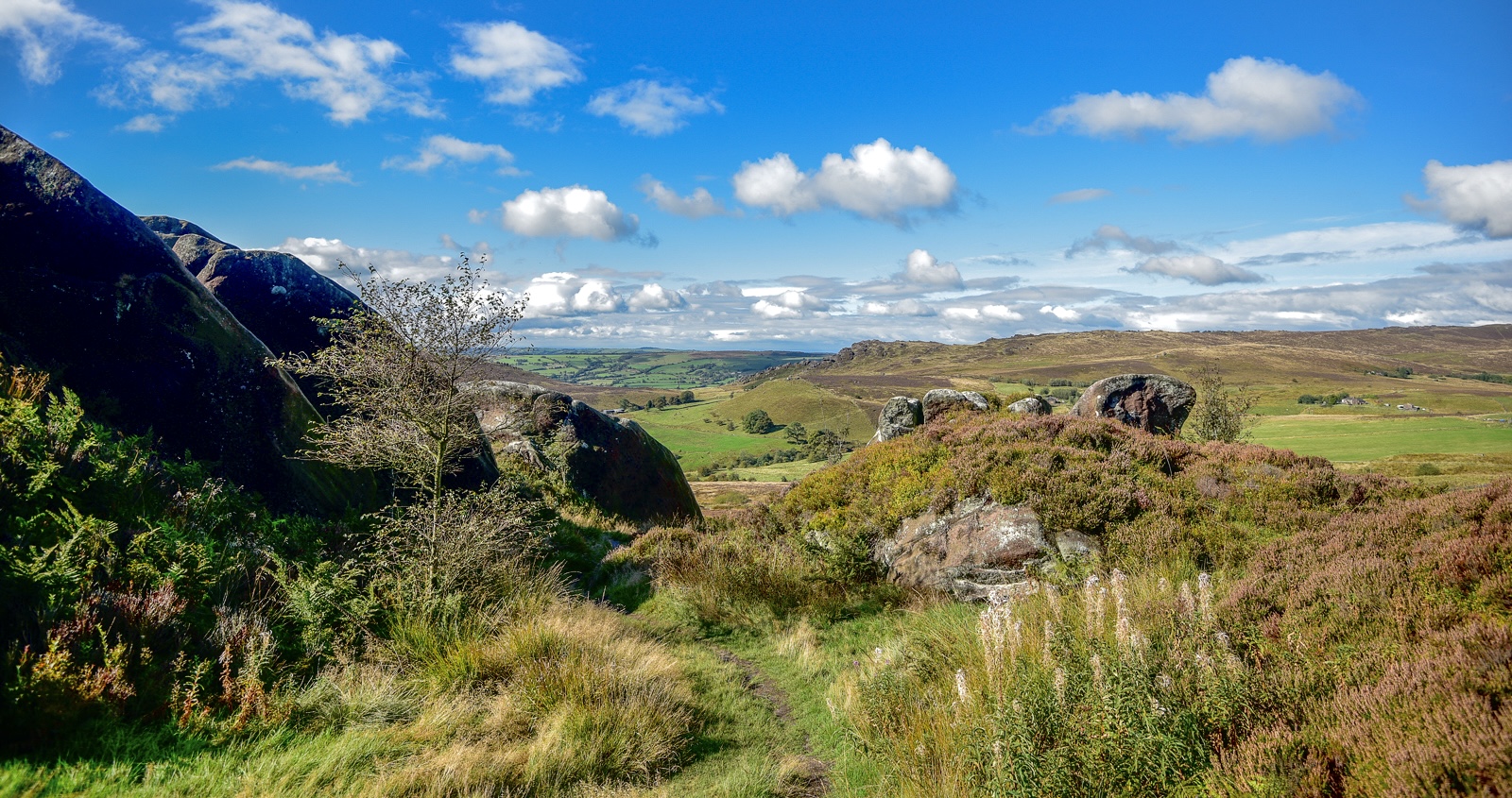 A view over rocks and hills with blue sky and some white clouds