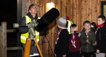 A group of children queuing up to look through a telescope